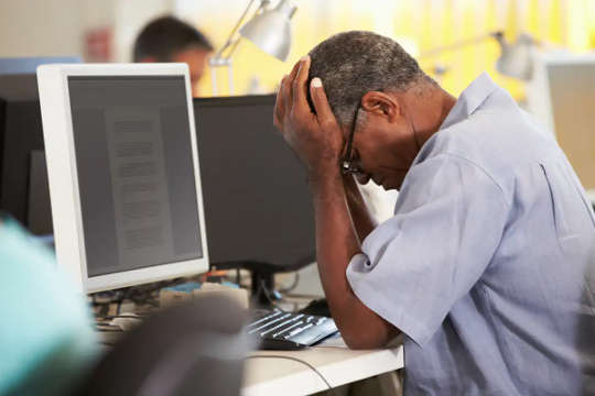 Chronic stress can lower your testosterone. man holding head in his hand in front of a computer screen