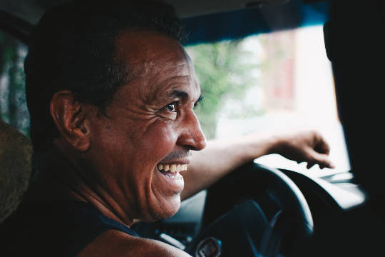 Today's Inspiration: December 11, 2022 a joyful smiling man at the wheel of a car