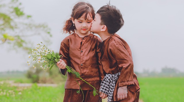 Parental Attitudes Shape Children's Sexual Interests and Play a young boy and girl, boy kissing girl on the cheek