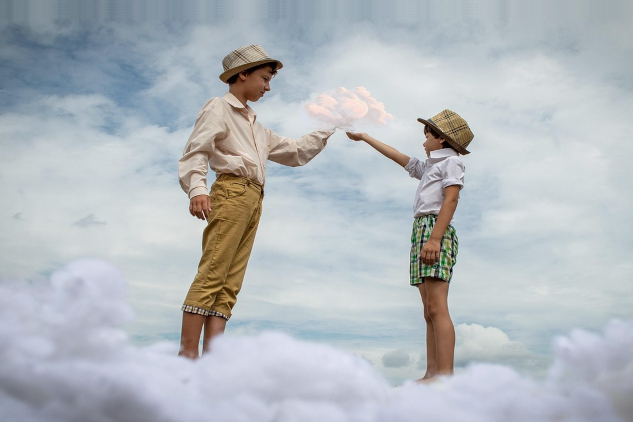 Are We Co-Dreaming the Universe Into Being? Two boys stretching their fingers to each other similar to the classic Michaelangelo image of God creating humanity. Image by Victoria from Pixabay.
